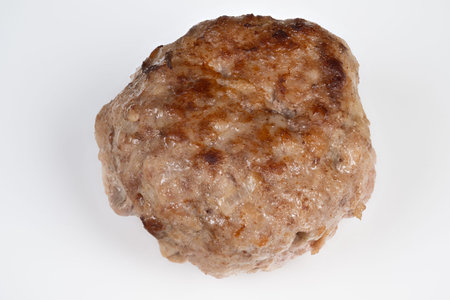 Browned meat cutlet isolated on white, studio closeup showing seared crust, coarse minced texture,...