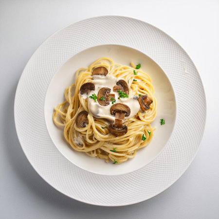 Spaghetti with mushrooms and cream sauce in a white plate on a white backgroundの素材