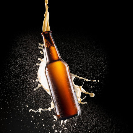 Bottle of beer with splashes and drops on black background.の素材