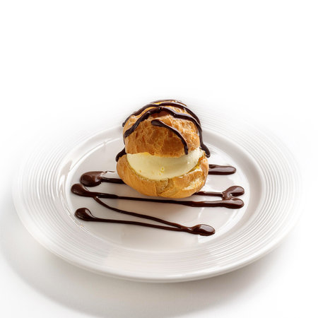 Eclair with chocolate cream on a white plate isolated on white backgroundの素材