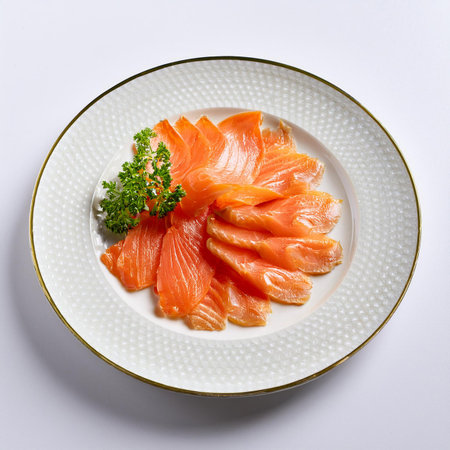 Slices of smoked salmon on a white plate with parsleyの素材