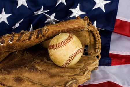 Old baseball in glove resting on American Flagの写真素材