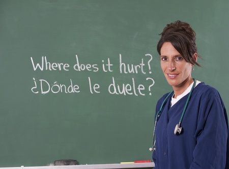 Nurse teacher translating English to Spanish on chalkboard of classroom. Focus is on teacher.の写真素材