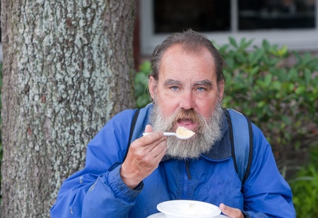 Portrait of poor homeless man eating foodの写真素材