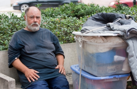 Poor homeless man on bench with possessions.の写真素材