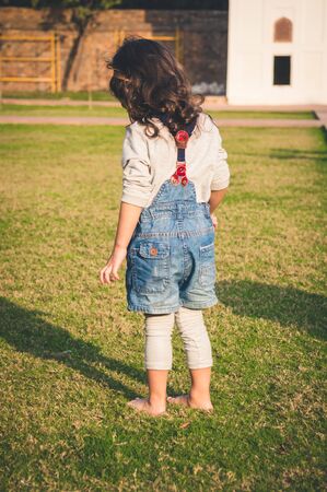 Little girl stepping on green grass barefootの写真素材