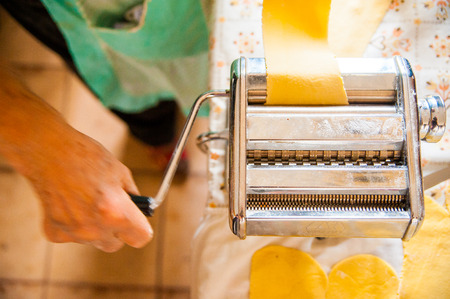 grandma using old machine to make pasta the old wayの写真素材