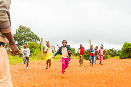 Bafoussam, Cameroon - 06 august 2018: young smiling african girls and boys running and having fun...