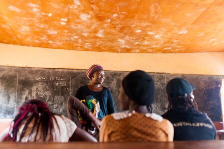 Bafoussam, Cameroon - 06 august 2018: young african woman teacher volunteer smiling during lesson in humble school classroomのeditorial素材