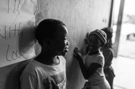 Bafoussam, Cameroon - 06 august 2018: black and white portrait of joyful smiling african boy in classroom with other children playingのeditorial素材