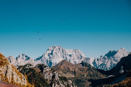 scary view of big majestic rocky dangerous mountains with birds flying over them in autumnの写真素材