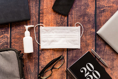 home working workplace kit on wooden office desk with hand sanitizer and 2020 agenda, a solution...