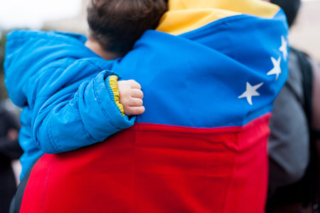 detail of little child hand on venezuelan flag as symbol of hope in future regime change, during march in support of Guaido governmentの写真素材