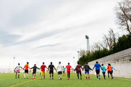 Barcelona, spain - 20 june 2020: a mixed race football team during practice holding hands, creating community and social inclusion with migrant young playersのeditorial素材