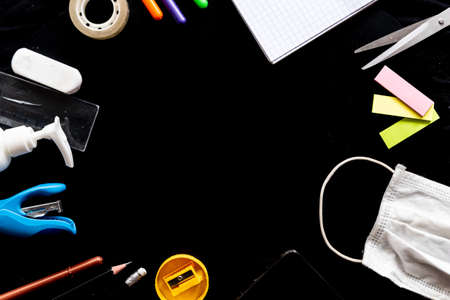 school equipment on black classroom desk, symbol of education and virus spread prevention in the time of covid19 with copy space, above viewの写真素材