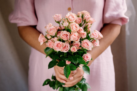 woman hands holding pink roses bouquet with pink dress. natural light. concept of spring season. soft light. blooming pink rosesの写真素材