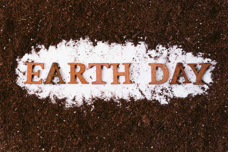 Earth day inscription with text made of wood cutout words on brown natural soil background.の写真素材
