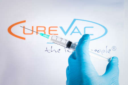 A hand holds a syringe in front of Curevac vaccine logo in Barcelona Spain, on May 18, 2021. Curevac is a new Covid19 vaccine produced in Germany, currently in the second phase of clinical trial.のeditorial素材