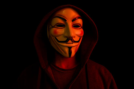New York, USA - 22 april 2021: man wearing vendetta mask with hoodie on black background. This mask is symbol for Anonymous hackers group and for anti system rebellions against governmentsのeditorial素材