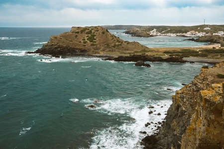 rocky beach landscape during storm with cloudy sky. Dramatic long exposure of sea waves breaking on rocks.の写真素材