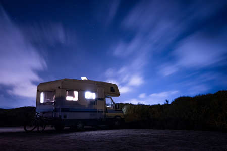 van life concept. long exposure of recreational vehicle, also called camper, parked at night under the stars with clear sky and view of milky way in the outdoorsの写真素材