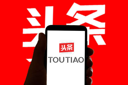 In this photo illustration the logo of the chinese app Toutiao is seen on the screen of mobile phone and of a laptop in Barcelona, Spain on November 4, 2021.のeditorial素材
