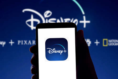 The Disney streaming app Disney+ logo is seen on the screen of a mobile phone and the display of a laptop in Barcelona, Spain on November 16, 2021のeditorial素材