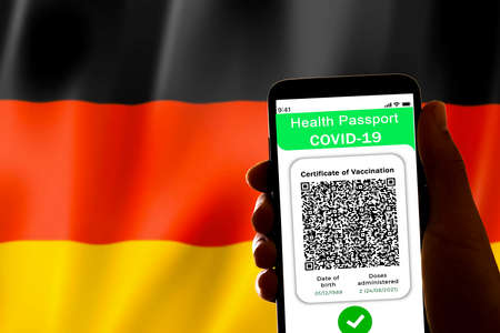 a Covid certificate, also called covid passport, is seen on the screen of a mobile phone with the german flag in the background in Barcelona, Spain on November 24, 2021.のeditorial素材