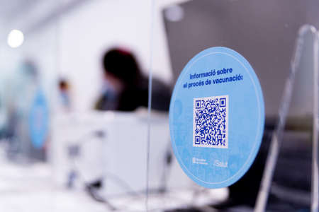 A sign in catalan language with a qr code regarding the Covid-19 vaccination process is seen at a vaccination center in Barcelona, Spain on December 22, 2021. Following the spread of the Omicron variant, the spanish government is pushing for older people のeditorial素材