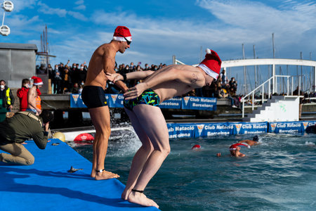 People dressed as Santa Claus jump on the Christmas traditional "Copa Nadal", Spain's oldest open water swimming competition, on Christmas in Barcelona, Spain on December 25, 2021.のeditorial素材