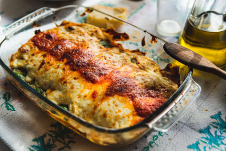 Cannelloni with spinach close up, tomato sauce, bachamel and cheese on table cloth. Traditional homemade classic italian cuisine concept.の写真素材