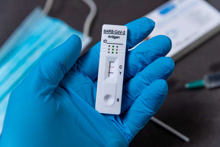 A hand wearing a protective glove is seen holding a rapid Covid test, also known as antigen test or lateral flow test, showing a positive result in a close up on a table in Barcelona, Spain on February 04, 2022.. Covid self tests demand has increased expoのeditorial素材