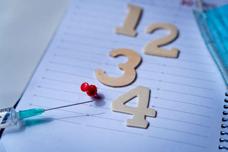 Four numbers are seen on an agenda as concept of 4th jab of Covid vaccination campaign against covid omicron variant. Numbers on calendar with as a concept for the fourth covid-19 vaccine dose.の写真素材