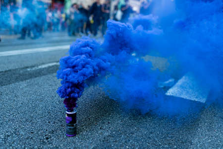 A blue smoke bomb is seen among protesters marching during a protest in the street with people uprisingの写真素材