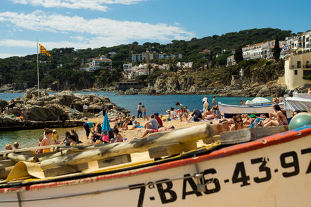 Calella de Palafrugell, Spain - 25 April 2022: Fishing boats and tourists on beach in Port Bo, old town of Calella de Palafrugell, in the Costa Brava shore Catalonia, Spain on a summer sunny day. Concept of tourism in Spain.のeditorial素材