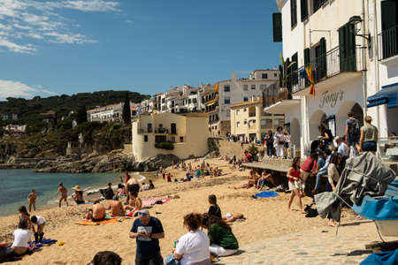 Calella de Palafrugell, Spain - 25 April 2022: Fishing boats and tourists on beach in Port Bo, old town of Calella de Palafrugell, in the Costa Brava shore Catalonia, Spain on a summer sunny day. Concept of tourism in Spain.のeditorial素材