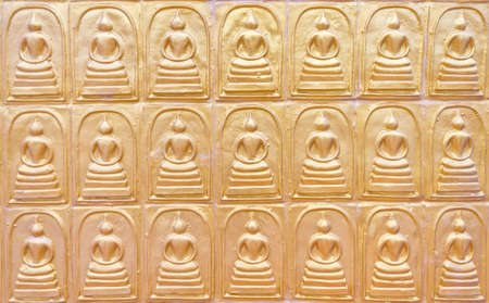 the row of buddha on the public temple wall in Thailandの写真素材