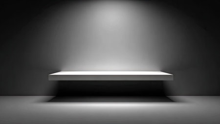 Minimalist, empty shelf set against a dark gray wall, illuminated by a spotlight from above, creating a bright, empty space for product presentation or showcasing.の素材