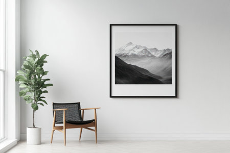 A modern living room showcases a framed black and white mountain landscape picture alongside a chair and plant.の素材