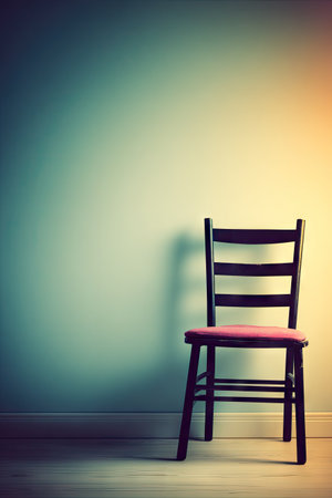 Single, dark wooden chair with a pink seat cushion is positioned near a wall in a room. The wall and chair are lit in a soft way, giving a mellow atmosphere to the scene. The floor is light wood toned.の素材