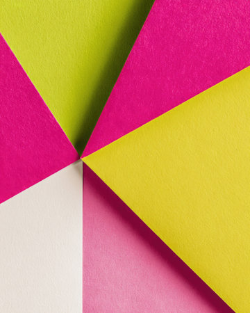 Vibrant design made from overlapping triangular shapes of various colors, including red, pink, magenta, lime green, yellow, and white.  The overlapping and juxtaposition of the colors create an eye-catching abstract pattern. The texture of the paper is visible.の素材