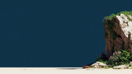 Dramatic scene featuring a rough, light-colored rocky outcrop covered partially by vibrant green foliage and small pink flowers, positioned on the right side of the frame above a pale, sandy or light-colored ground plane, set against an expansive, uniform dark blue background that provides significant negative space.の素材