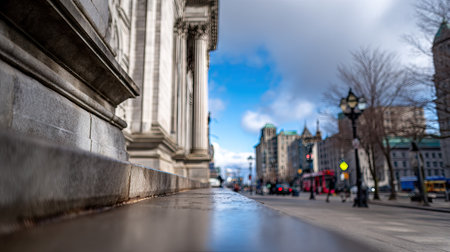 An architectural photograph showcases a classical building facade with columns, contrasting with a blurred street scene. The image displays a day environment with overcast skies. The composition provides potential for commercial usage in architecture, urban landscapes, or historical contexts.の素材