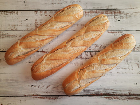 Three loaves of bread close-up on top of aged and white wooden countertop