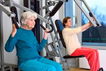 Two Senior Women Doing Chest Press Exercise at the Fitness Gym, Emphasizing Healthy Lifestyle.