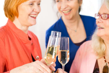 Close up Glasses of Tasty White Wine Tossed by Happy Adult Lady Friends to Celebrate Something.の写真素材