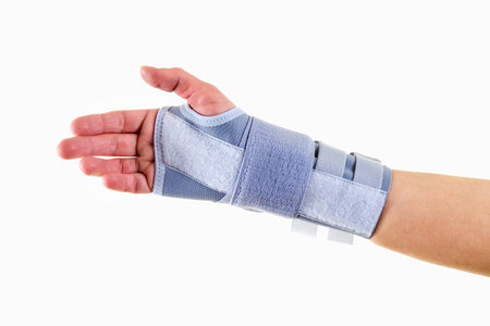 Close Up of Man Wearing Supportive Orthopedic Wrist Brace in Studio with White Background and Copy...