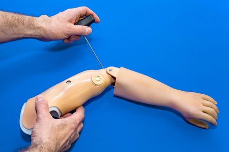 Top down view of hands working on artificial prosthetic arm in light skin tone color over isolated...
