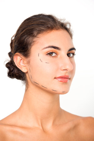Portrait of confident young woman with markings on face against white background.の写真素材