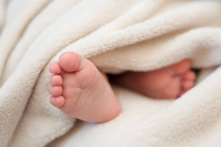feet sleeping baby  sticking out from under the blanketの写真素材
